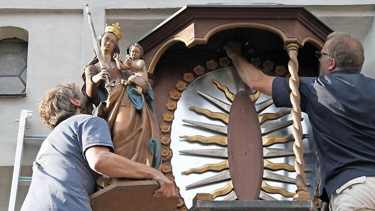 Stefan Lochner hebt die Muttergottes in das Kapellchen, während Norbert Düring die letzten Schrauben festdreht.Fotos: Heike Beudert