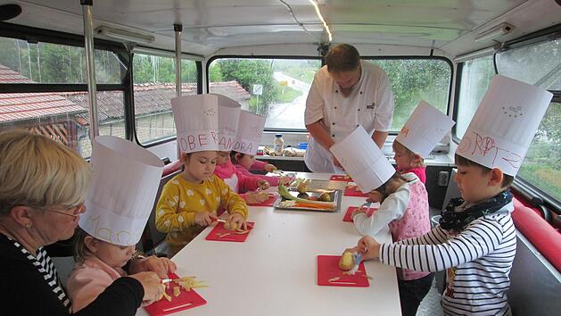 Vor dem Mittagessen im Koch-Bus ist Kartoffelschälen und Fritten schnipseln angesagt. Martin Schneider (Mitte) und Kita-Leiterin Heike Schöne-Krämer (links) geben Tipps dazu.