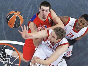 Mit viel Energie tippt Youngster Patrick Heckmann (vorn) den Ball in den Korb und setzt sich dabei gegen Superstar Nando de Colo (l.) durch. Rechts versucht Darius Miller, den Franzosen wegzudrücken. Foto: Daniel Löb