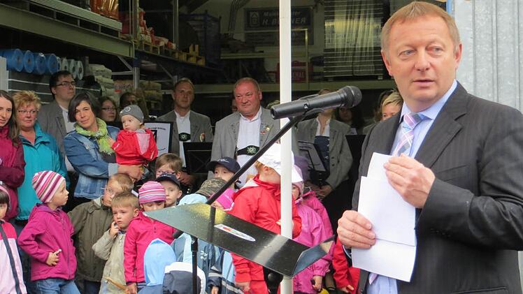 - Landrat Thomas Bold bei seiner Ansprache. Im Hintergrund die Kindergartenkinder und Dirigent Rudolf Müller.