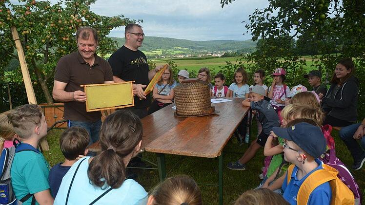 So sehen Waben mit Wachsdeckelung vor dem Schleudern aus. Nach dem Schleudern erhält man leckeren Honig, erklären Imker Stefan Scherbel (r.) und 3. Bürgermeister Klaus Dressel den Kids. Foto: K.-H. Hofmann