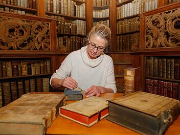 Die Buchrestauratorin der Bamberger Staatsbibliothek, Regine Ullein, begutachtet ein Buch aus dem Jahr 1794.  Fotos: Matthias Hoch