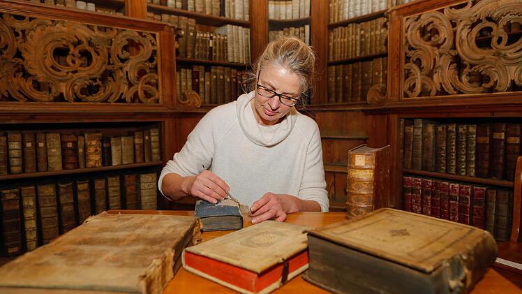 Die Buchrestauratorin der Bamberger Staatsbibliothek, Regine Ullein, begutachtet ein Buch aus dem Jahr 1794.  Fotos: Matthias Hoch