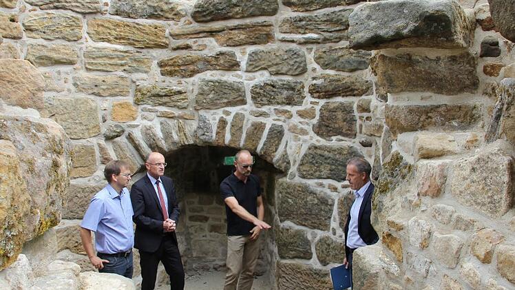 Architekt Jürgen Bergmann (Zweiter von rechts) zeigt Bernhard Joos, Landrat Schneider und Maroldsweisach Bürgermeister Wolfram Thein (weiter von rechts), wie hoch der Schutt im Wehrturm lag. Foto: Ralf Kestel