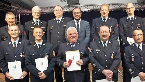 Landrat Sebastian Straubel (obere Reihe, Vierter von links) zeichnete Wehrmänner in der Stadt Neustadt für 25 beziehungsweise 40 Jahre aktiven Dienst mit Ehrenzeichen aus. Fotos: Michael Stelzner