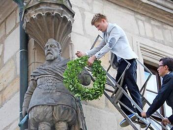 Tradition, Tradition: Der erste Kranz kommt an den Arm der Fürstenstatue, der zweite auf den Kopf. Ganz oben auf der Leiter steht der Festredner (Max Bauer), danach kommen die fünf Jahrgangsbesten der Q11, angeführt von Michael Engel. Nach der Bekränzung muss der Festredner noch drei Gläser Bier austrinken und zu Boden werfen.  Foto: Simone Bastian