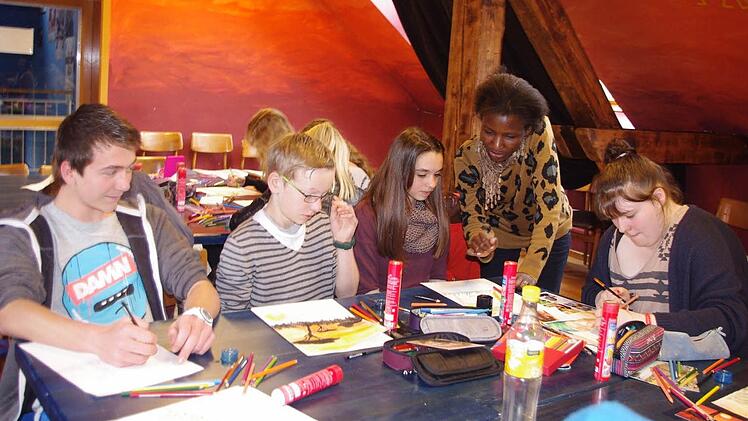 Jonas Beetz, Tim Büttner, Nadine Müller und Anna Krieg lassen sich von Noeline Aasike die afrikanische Malweise erläutern. Foto: Heike Schülein