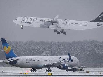 Während eine Lufthansa-Maschine der Star Alliance landet, wartet am Flughafen von Frankfurt am Main  eine Condor-Maschine auf den Start. Durch die heftigen Schneefälle kam es zu Verspätungen und Flugausfällen. Foto: Arne Dedert/dpa