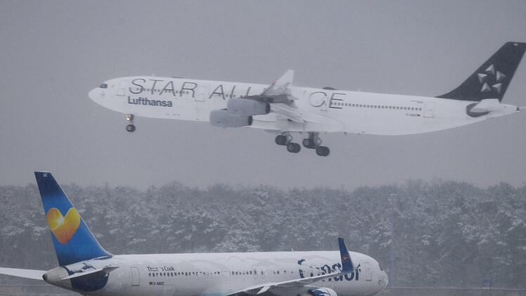 Während eine Lufthansa-Maschine der Star Alliance landet, wartet am Flughafen von Frankfurt am Main  eine Condor-Maschine auf den Start. Durch die heftigen Schneefälle kam es zu Verspätungen und Flugausfällen. Foto: Arne Dedert/dpa