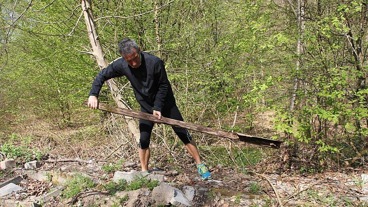 Hubert Karl zeigt, was übrig ist vom Zeiler Trimm-Dich-Pfad: Das halb verrottete Schild, das die Station 15 (Fuß-Erlebnis-Pfad) beschreibt, hat er aus dem Gestrüpp hervorgezogen. Aber gelogen ist es ja nicht, was da drauf steht: Es ist immer noch ein Fuß-Erlebnis, wenn man über die Reste der Station hinweg läuft. Fotos: Andreas Lösch