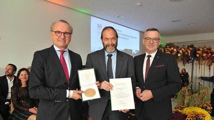 Der Ha&szlig;furter G&auml;rtnermeister Werner Pudell (Mitte) erhielt bei der Schlussveranstaltung der IGA in Berlin durch BMLE-Ministerialdirektor Clemens Neumann (links) und J&uuml;rgen Mertz, Pr&auml;sident des Zentralverbandes Gartenbau, den Staatsehrenpreis in Gold. Thomas Uhlemann