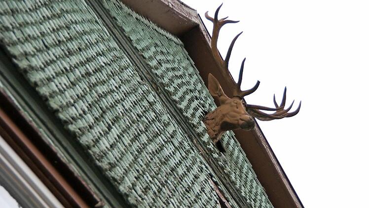 Vom Giebel blickt ein Hirschkopf herab.