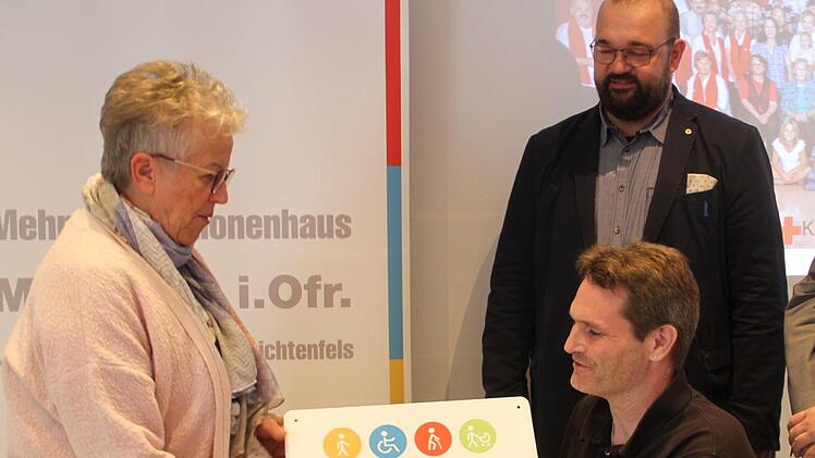 Architekt Johannes Morhard (2. v. li.) und sein Mitarbeiter Marc Friedrich (sitzend) übergaben das Signet "Bayern barrierefrei" an die stellvertretende BRK-Vorsitzende Rosemarie Göhring (links).