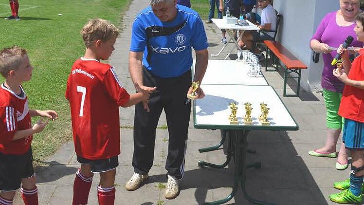 Während Jugendleiter Georg Renk (links) die Pokale an die Siegermannschaft des TSV Weißenbrunn übergibt, bedankt sich ein Spieler (rechts) für die Einladung zum Turnier; dahinter Schirmherrin Karin Hafermann.