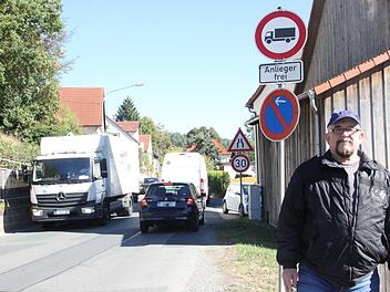 Anwohner Dieter Herlein steht vor dem Schild in Hummendorf, das eigentlich Lkw die Durchfahrt verbietet. Foto: Franziska Rieger