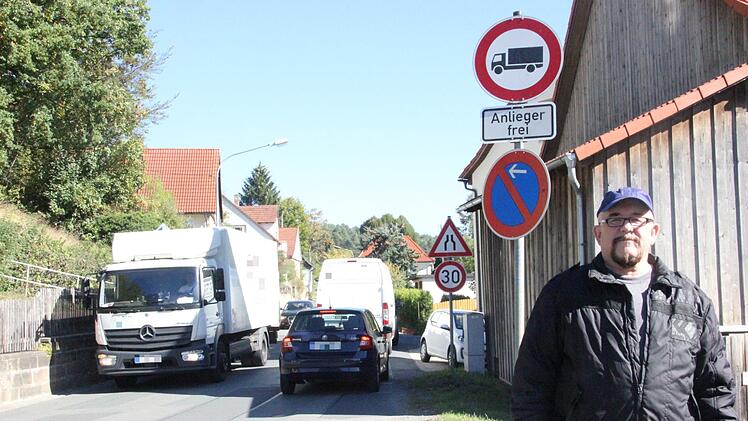 Anwohner Dieter Herlein steht vor dem Schild in Hummendorf, das eigentlich Lkw die Durchfahrt verbietet. Foto: Franziska Rieger