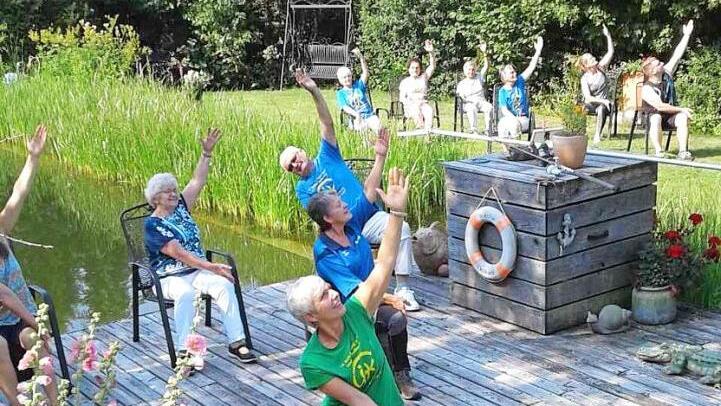 Morgenyoga am Teich kann im Sitzen und im Stehen ausgeführt werden, wichtig sind die Bewegung und der Spaß, sagt Trainerin Birgit Schmitt (vorne im grünen T- Shirt).  Foto: K.- H. Hofmann