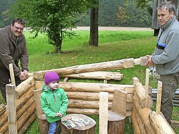 Die zweijährige Luisa Friedrich macht es sich im Blockhaus schon mal bequem, während Uwe Döring und Klaus Blaß vom Jugendwaldheim Lauenstein noch an den Wänden werkeln. Fotos: Sonja Adam