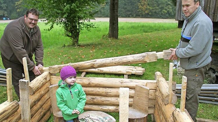 Die zweijährige Luisa Friedrich macht es sich im Blockhaus schon mal bequem, während Uwe Döring und Klaus Blaß vom Jugendwaldheim Lauenstein noch an den Wänden werkeln. Fotos: Sonja Adam