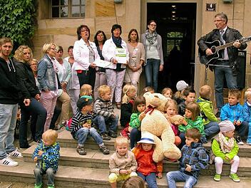Übergabe von Urkunde und Maskottchen geschahen mit musikalischer Begleitung durch Landrat Michael Busch auf der Treppe zum Gemeindehaus. Foto: Klaus Oelzner