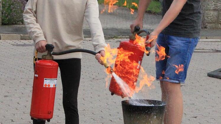 Im Team wird ein brennender Papierkorb gelöscht. Foto: Matthias Einwag