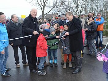Bürgermeister Rainer Detsch, umrahmt von Kindern, durchschnitt im Beisein zahlreicher Bürger und Ehrengäste das Band und gab die Haßlachbrücke Wolfersdorf für den Verkehr frei.  Foto: K.-H. Hofmann