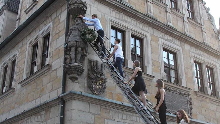Der Schüler-Sprecher wird gewählt, darf eine Ansprache halten und die Statue von Herzog Casimir bekränzen. Hinter ihm stehen die fünf Jahrgangsbesten der Q11 (von oben nach unten): Maximilian Kurth, Katharina Schmdit, Lina Richter, Hannah Triebel, Christina Keßler und Anna Kiesewetter.