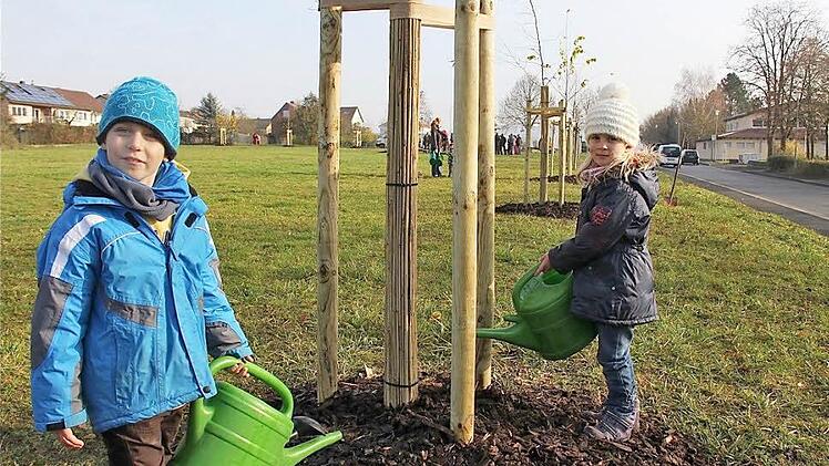 Lucas Väth (links) und Hanna Glückler gießen ihren Familienbaum, der an Hannas Geburtstag erinnern soll. Foto: Gerd Schaar