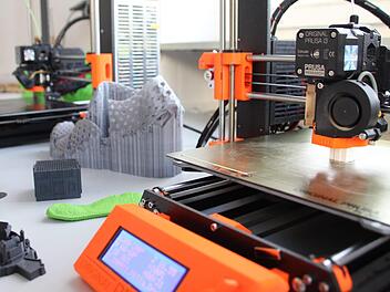 Der 3D-Drucker stellt die weiße Miniatur (rechts unter dem Druckkopf) etwa 40 Minuten lang her.