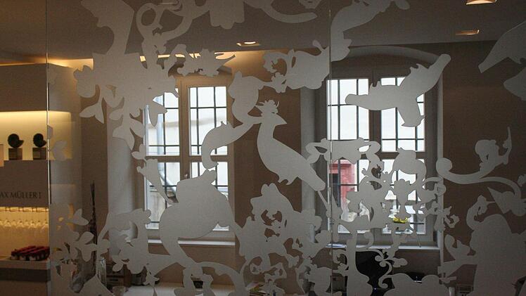 Die prächtigen, sandgestrahlten Ornamente auf den drei raumhohen Glaselementen schirmen das Büro leicht ab.