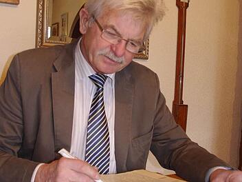 Manfred Schubert blättert im alten Protokollbuch des ehemaligen Kirchenbauvereins Höfles.