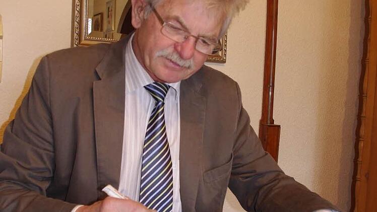 Manfred Schubert blättert im alten Protokollbuch des ehemaligen Kirchenbauvereins Höfles.