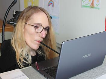 Weil Nina Hofmann ihre Arme und Beine nicht bewegen kann, schreibt sie am Laptop ihre Texte mit einem Mundstab.  Foto: Carsten Höllein
