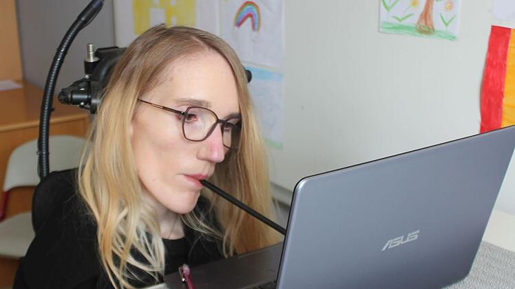 Weil Nina Hofmann ihre Arme und Beine nicht bewegen kann, schreibt sie am Laptop ihre Texte mit einem Mundstab.  Foto: Carsten Höllein