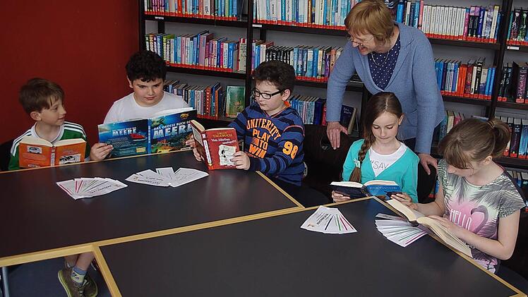 Simon Fritz, Mert Düzardic, Jakob Lux, Sophie Bechauf und Amelie Schreier (v. l.) schmökern in Büchern. Vor sich haben sie ihre Lese-Fächer "Textknacker" liegen. Mit im Bild ist Direktorin Renate Leive. Foto: Heike Schülein
