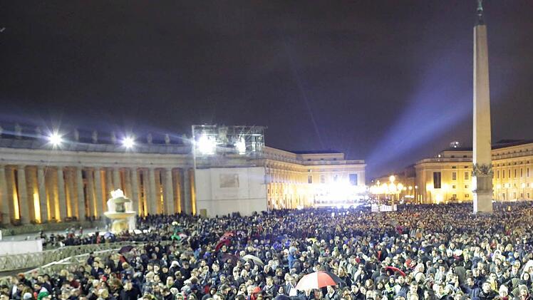 Auf dem Petersplatz haben sich am 12.03.2013 vor dem Petersdom zahlreiche Menschen versammelt. Sie warten auf das Ergebnis des ersten Wahlgangs der Papstwahl. Mit schwarzem Rauch würde ein erfolgloser Wahlgang signalisiert, weißer Rauch heißt: ein neuer Papst wurde gewählt. Die Kardinäle im Konklave bestimmen bei der Papstwahl den Nachfolger von Papst Benedikt XVI. Foto: Michael Kappeler/dpa