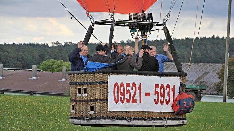 Los geht"s. Der Ballon hat abgehoben. Richard Ebert (links), Ballonpilot Reiner Hoch (rechts) und die weiteren Mitfahrer winken dem "Bodenpersonal."