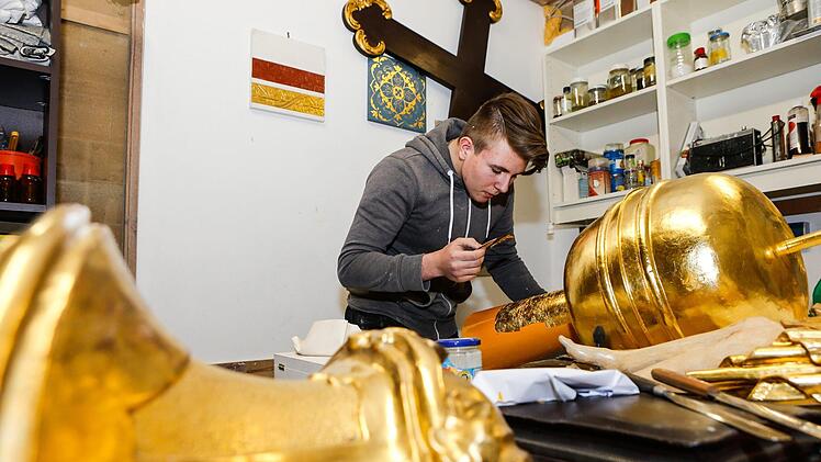 Lukas Nagel beim "Anschie&szlig;en". Der Azubi vergoldet hier den Unterbau eines Kreuzes vom Querhaus der Kirche St. Michael in Bamberg.