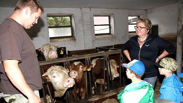 Florian Grau stellt den Kindern die Tiere auf seinem Bauernhof vor, rechts Kreisb&auml;uerin Evi Derrer. Foto: Richard S&auml;nger
