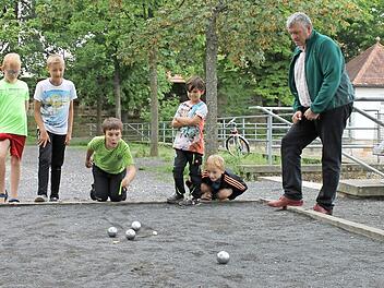 Der Bürgermeister als Boule-Lehrer: Jürgen Hennemann zeigte den Kindern, wie das Spiel mit den Metallkugeln funktioniert. Foto: Janina Reuter