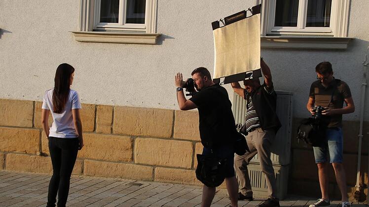So sieht es aus, wenn Porträtfotos gemacht werden: Miriam steht Modell, Stefan Hemmerlein fotografiert, ein weiterer Fotograf lenkt das Abendlicht mit den Reflektor und die anderen warten darauf, dranzukommen.Matthias Einwag
