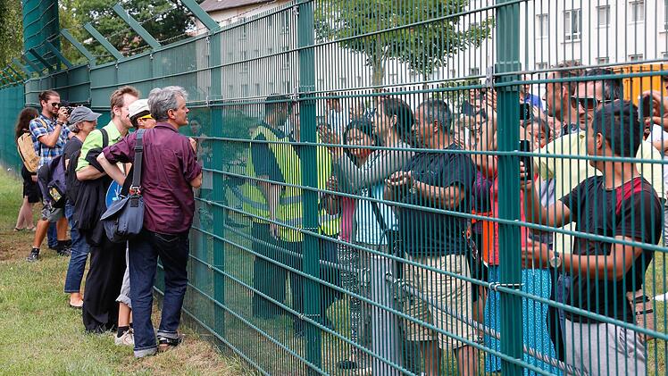 Szenen wie diese spielten sich am Donnerstag in der Bamberger Birkenalle ab. Flüchtlinge und Demonstranten gegen das Abschieblager sprechen durch den Zaun miteinander.   Fotos: Matthias Hoch