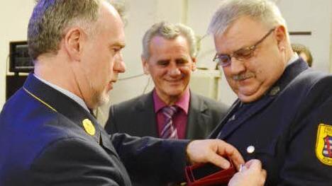 Kreisbrandrat Joachim Ranzenberger (links) dekoriert die Uniform von Helmut Weidmann mit dem Ehrenzeichen des Freistaates Bayern in Gold für 40-jährige Dienstzeit. Die Urkunde überreichte Landrat Oswald Marr (Mitte). Fotos: K.-H. Hofmann