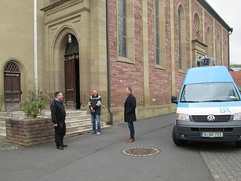 Pfarrer Norbert Wahler, Bauhofangestellter Chrisrian Reusch und Bürgermeister Johannes Krumm (von links) lauschen neben dem BR-Aufnahmefahrzeug dem Zwölf-Uhr-Läuten. Foto:  Winfried Ehling