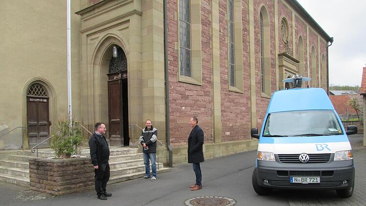 Pfarrer Norbert Wahler, Bauhofangestellter Chrisrian Reusch und Bürgermeister Johannes Krumm (von links) lauschen neben dem BR-Aufnahmefahrzeug dem Zwölf-Uhr-Läuten. Foto:  Winfried Ehling