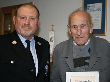 1. Vorsitzender Helmut Schuster dankt Alois Gaßner, der seit 65 Jahren Mitglied der FFW Münsterschwarzach ist, mit einer Urkunde. Foto: Pfannes
