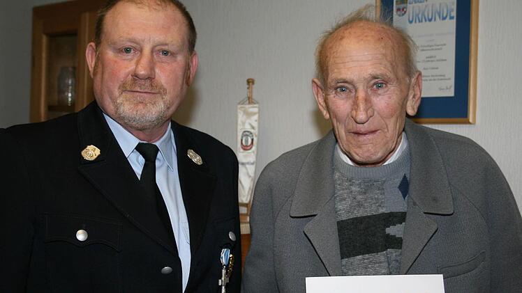 1. Vorsitzender Helmut Schuster dankt Alois Gaßner, der seit 65 Jahren Mitglied der FFW Münsterschwarzach ist, mit einer Urkunde. Foto: Pfannes