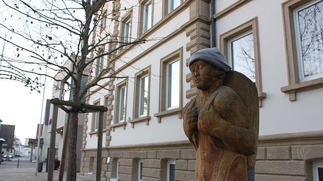 Korbmacherfigur (von jemandem mit einer M&uuml;tze versehen) vor dem Michelauer Rathaus. Wer hier der neue Chef wird, entscheiden die B&uuml;rger im April. Foto: Ramona Popp