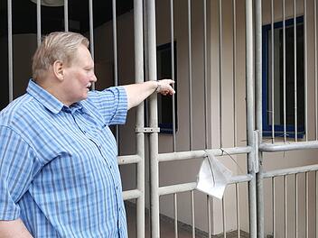 Wer durch das Gittertor schaut, das den Durchgang zum ehemaligen Rewe-Markt in der Hauptstraße verschließt, sieht hinter den  Fenstern noch Märchen-Motive an der  Wand, zeigt Wolfgang Döring. Foto: Christofzik