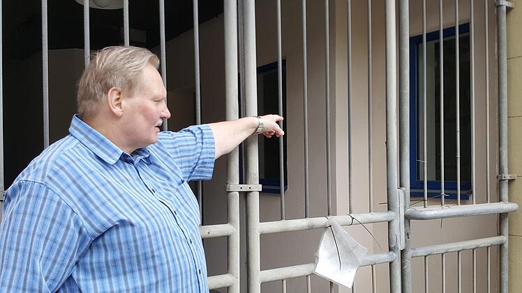 Wer durch das Gittertor schaut, das den Durchgang zum ehemaligen Rewe-Markt in der Hauptstraße verschließt, sieht hinter den  Fenstern noch Märchen-Motive an der  Wand, zeigt Wolfgang Döring. Foto: Christofzik